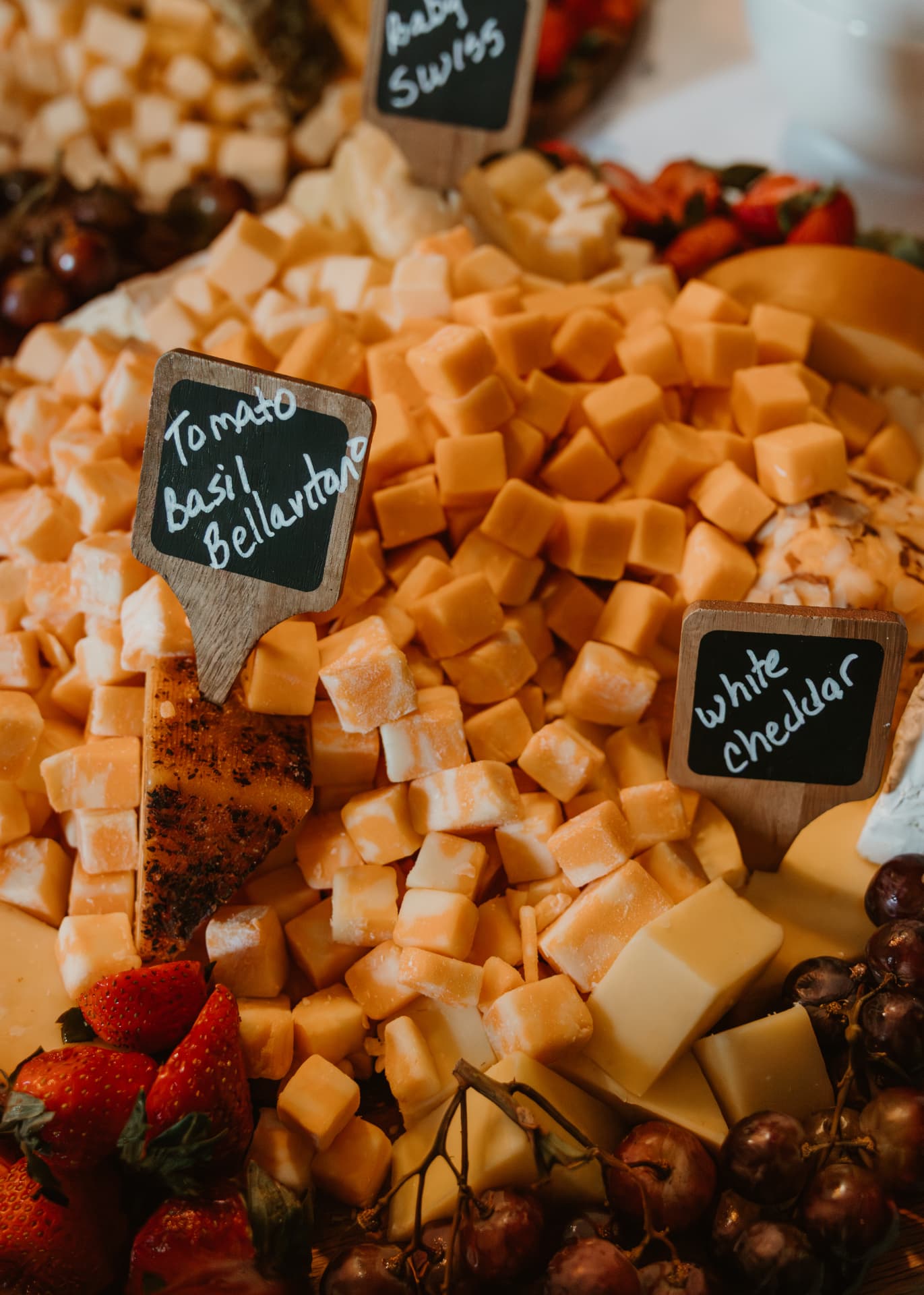 Artisan cheese display with chalkboard labels, strawberries and grapes