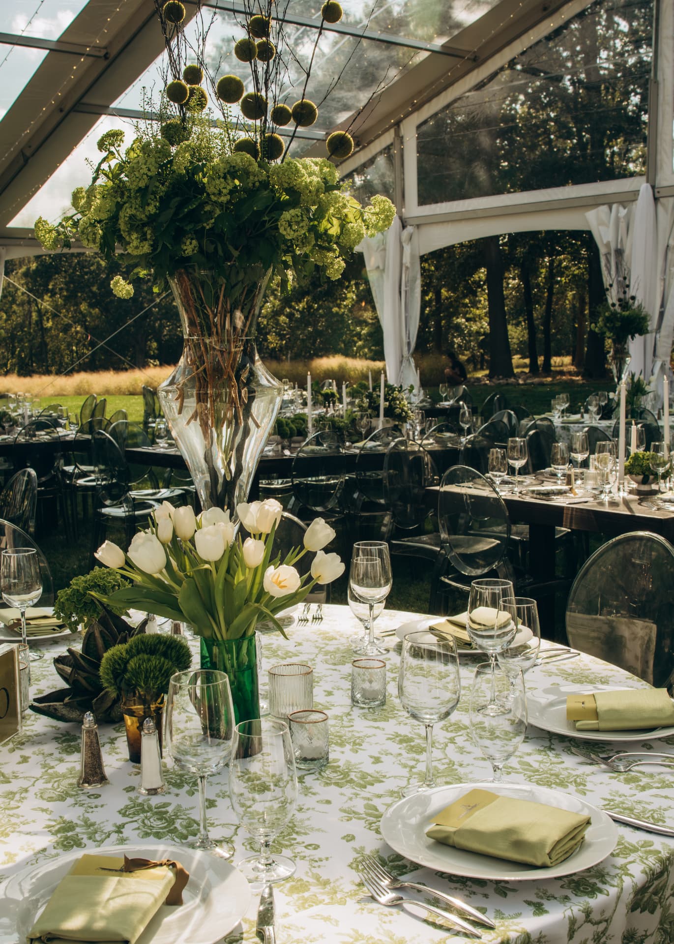 Tall floral centerpiece and white tulips on a garden-print tented table
