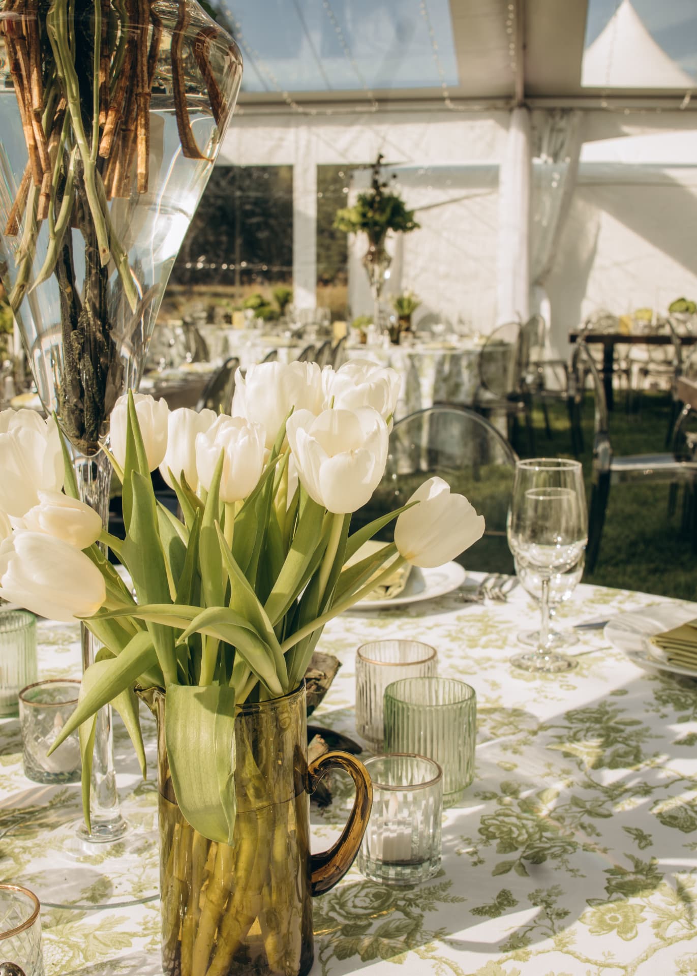 White tulips in an amber pitcher on a sunlit reception table