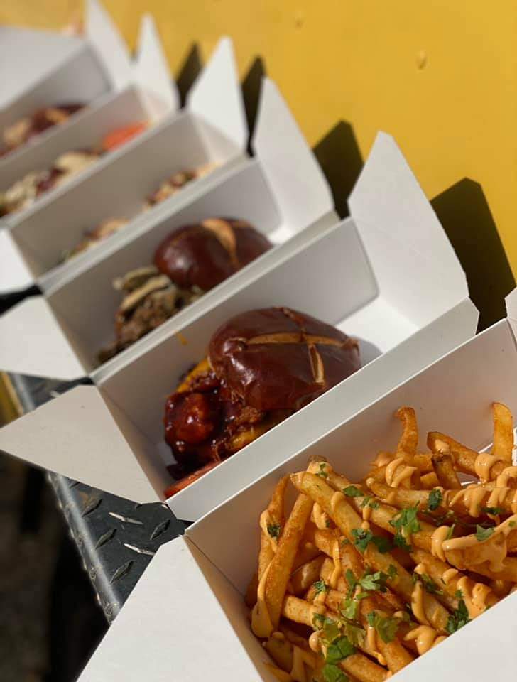 Food truck boxes with pulled pork sandwiches and sauced seasoned fries