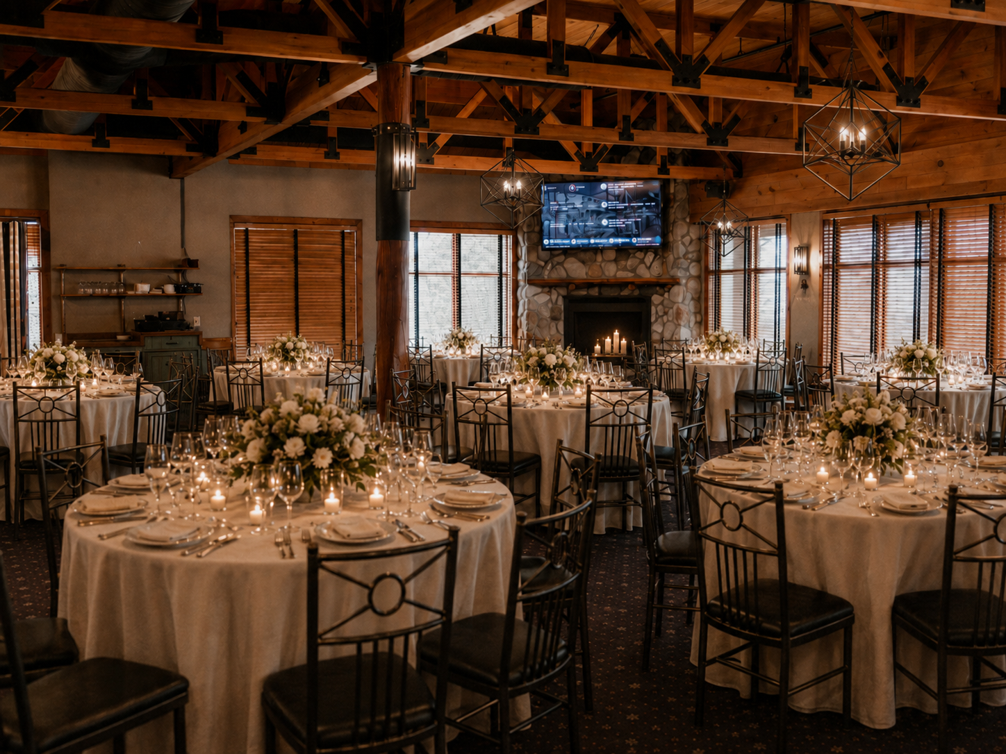 Upper Dining Room at Redwood set with round tables, ivory linens, white floral centerpieces and candlelight for a wedding reception