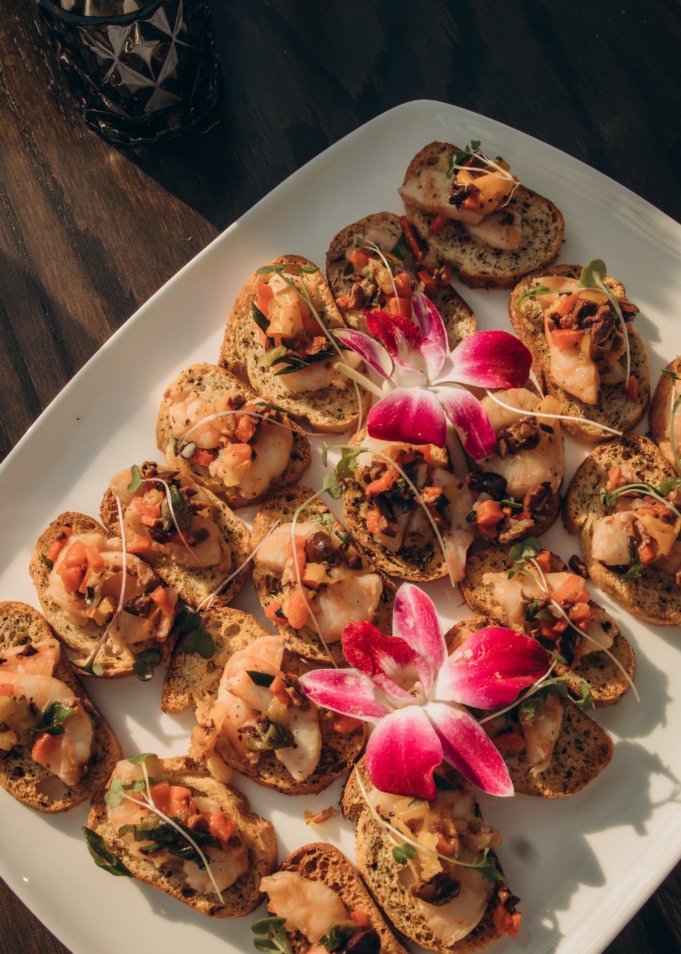 Platter of shrimp and seafood crostini garnished with orchids